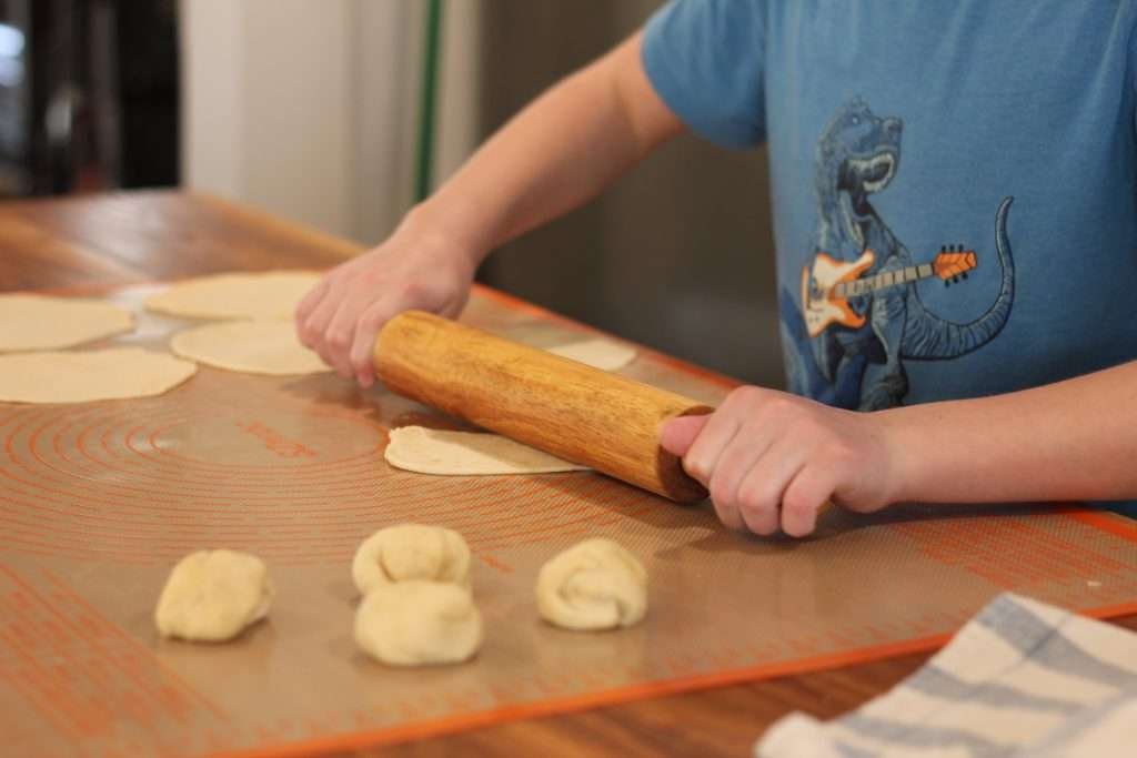 boy rolling out sourdough tortillas