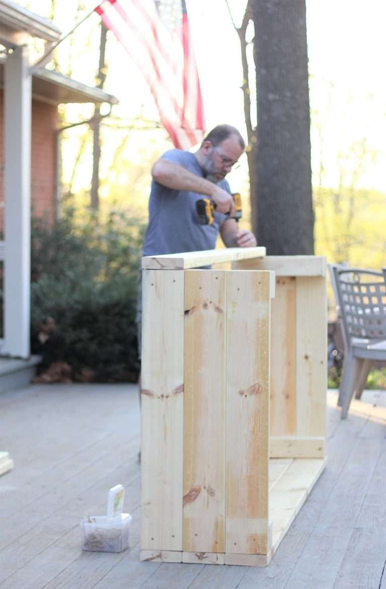 Man building raised garden boxes with American Flag in the background