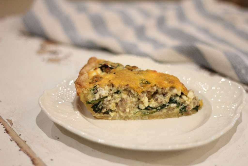 slice of sausage spinach quiche on plate