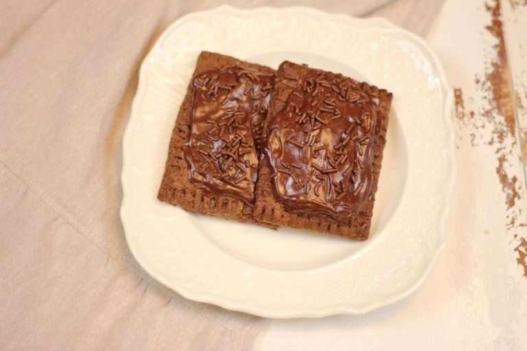 Two Homemade Chocolate Pop Tarts with Fudge frosting on white plate.