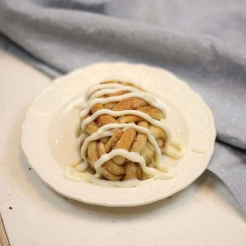 Sourdough Cinnamon roll twists with cream cheese frosting on plate.