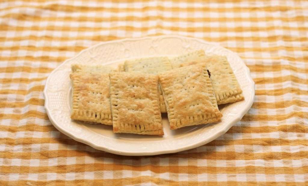 A plate of homemade pop tarts on it on top of a yellow check cloth.