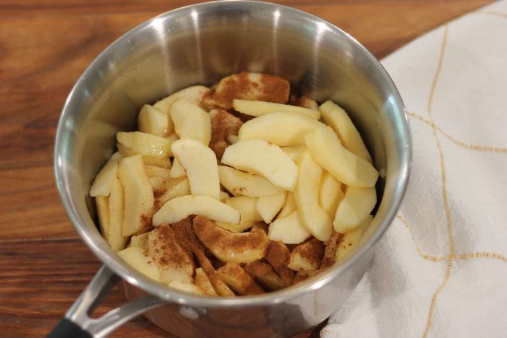 Apples sliced in pot with spices sprinkled on top.